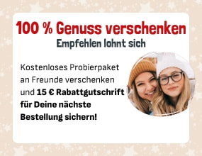 „Zwei lächelnde Frauen in Winterkleidung mit Text: ‚100 % Genuss verschenken – kostenloses Probierpaket verschenken und 15 € Rabattgutschrift sichern‘.“