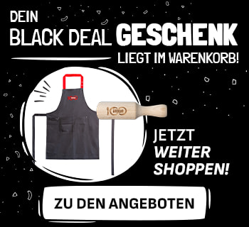 Werbebanner mit schwarzem Hintergrund und dem Text „Dein Black Deal Geschenk liegt im Warenkorb! Jetzt weiter shoppen! Zu den Angeboten“. Links sind eine schwarze Kochschürze mit roten Trägern  und eine  hölzerne Gewürzschaufel