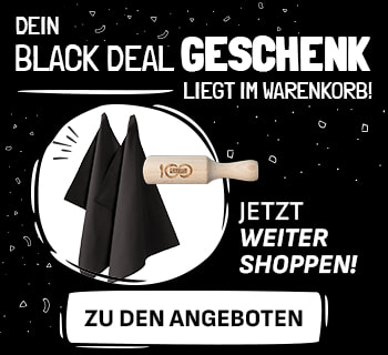 Werbebanner mit schwarzem Hintergrund und weißer Schrift: „Dein Black Deal Geschenk liegt im Warenkorb! Jetzt weiter shoppen!“. Links sind zwei schwarze Stoffservietten und ein hölzernes Nudelholz mit Gravur abgebildet. Rechts befindet sich ein weißer Button mit der Aufschrift „Zu den Angeboten“