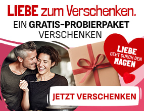 Lächelndes Paar mit Geschenkbox mit roter Schleife. Text: „Liebe zum Verschenken – Ein Gratis-Probierpaket verschenken“, Herzsymbol mit Schriftzug „Liebe geht durch den Magen“.
